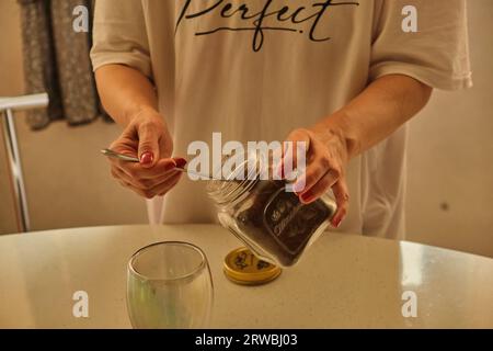 Donna che versa caffè caldo in tazza al mattino dalla pentola. Casalinga a casa, preparare caffè macinato fresco in cucina per colazione, bere, macinare cof Foto Stock