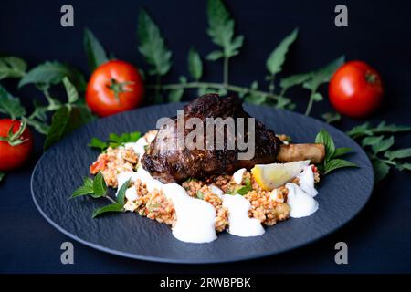 Codolo di agnello grigliato al carbone con bulgur e crema all'aglio Foto Stock