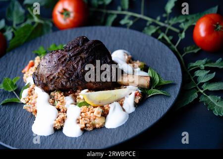 Codolo di agnello grigliato al carbone con bulgur e crema all'aglio Foto Stock