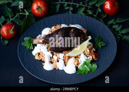 Codolo di agnello grigliato al carbone con bulgur e crema all'aglio Foto Stock