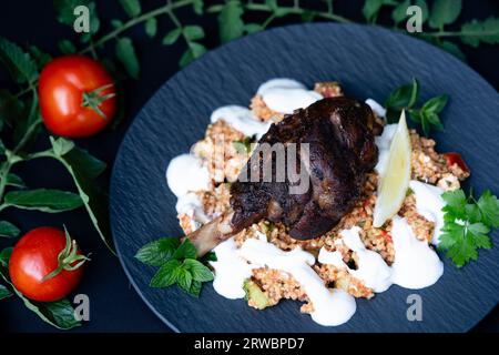 Codolo di agnello grigliato al carbone con bulgur e crema all'aglio Foto Stock