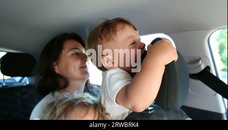 Madre che tiene il bambino in auto sul sedile posteriore senza protezione, piangendo il bambino Foto Stock