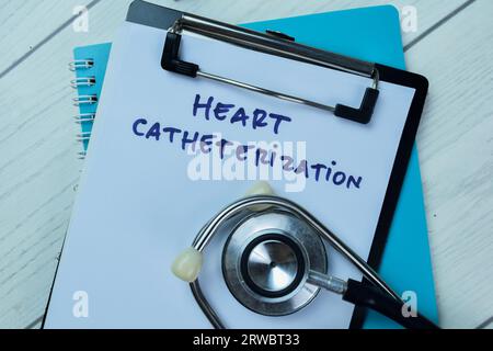 Concetto di cateterizzazione cardiaca scrivere su documenti cartacei con stetoscopio isolato su un tavolo di legno. Foto Stock
