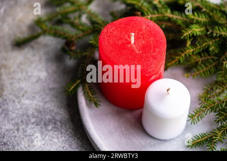 Sopra le candele poste su una superficie in ceramica grigia vicino a rametti di abete verde come simbolo del Natale Foto Stock