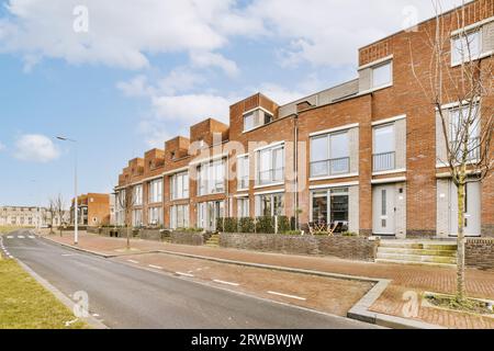 Strada vuota che passa attraverso edifici residenziali di fila contro il cielo nuvoloso della città durante il giorno Foto Stock
