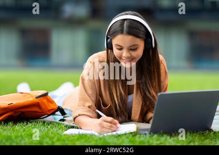 Studentessa intelligente che si aggrappa al parco, partecipando al webinar Foto Stock