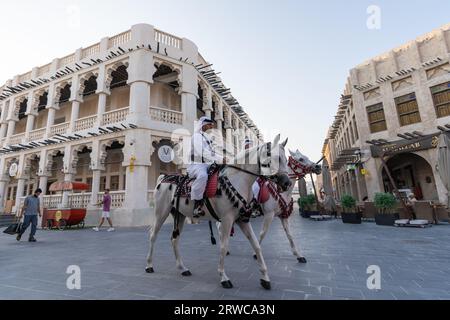 Doha, Qatar - 17 ottobre 2022: Polizia turistica in abiti tradizionali del Qatar pattuglia lungo la passerella nel Souq Wakif. Foto Stock