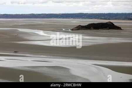 panorama da St Michel in Normandia in Francia durante la bassa marea e gruppi di turisti in mezzo alla spiaggia Foto Stock