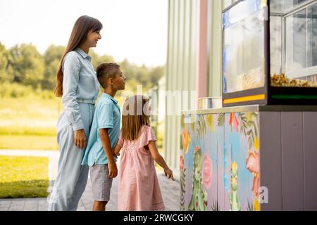 Mamma con bambini in attesa di un dolce zucchero di cotone al parco divertimenti Foto Stock