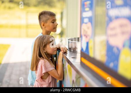 Bambina e ragazzo in attesa di un dolce zucchero di cotone al parco divertimenti Foto Stock