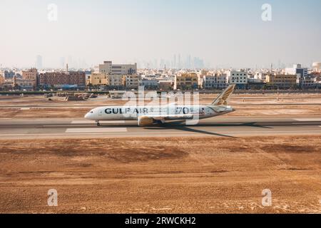 Un Boeing 787 Gulf Air sulla pista dell'aeroporto internazionale del Bahrain, Bahrain, con Muharraq e Manama City fotografate alle spalle Foto Stock