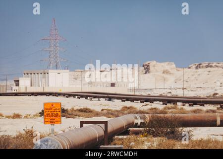 Un gasdotto con un cartello di avvertimento nel deserto del Bahrein Foto Stock