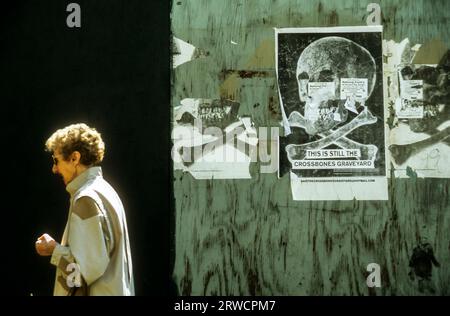 Una donna che passa un poster sul Crossbones Graveyard a Redcross Way, Southwark, Londra. Foto Stock