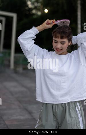 Una ragazza attraente si pettina i capelli per strada. Pettine. Foto Stock