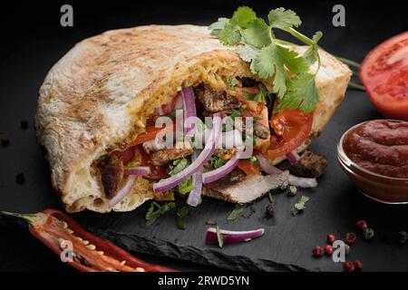 Deliziosa pita farcita con carne tenera, verdure fresche e spezie aromatiche Foto Stock