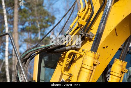 Primo piano dei tubi flessibili idraulici, dei tubi, dei raccordi e dei cilindri su una macchina escavatrice funzionante. Foto Stock