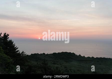 Vista dell'alba da Seongsan Ilchulbong sull'isola di Jeju, Corea del Sud, con parte del cratere vulcanico in primo piano. Foto Stock