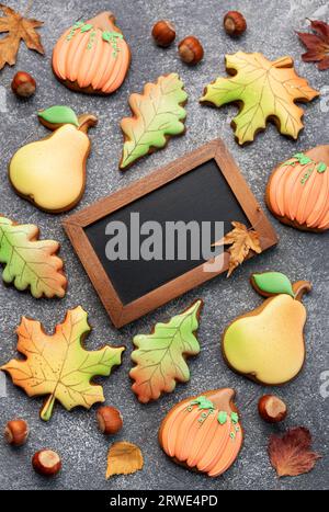 Biscotti autunnali multicolori fatti in casa e lavagna vuota su sfondo scuro. Foto Stock