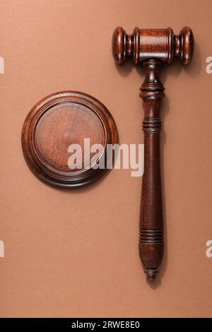 Un martelletto di mogano di legno con blocco sonoro su sfondo marrone Foto Stock