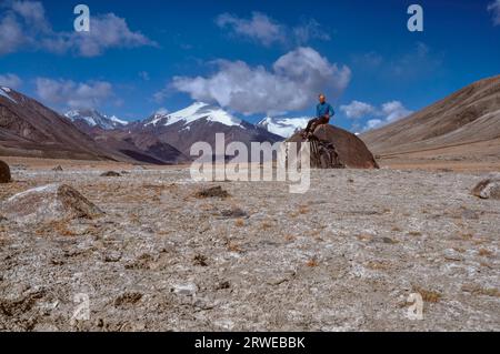 Giovane escursionista seduto sulla roccia alta nel Pamir Mountains in Tagikistan Foto Stock