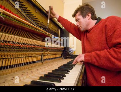 Una professione che svanisce. Un sintonizzatore di pianoforte professionale al lavoro che sintonizza un vecchio pianoforte verticale tedesco. Foto Stock