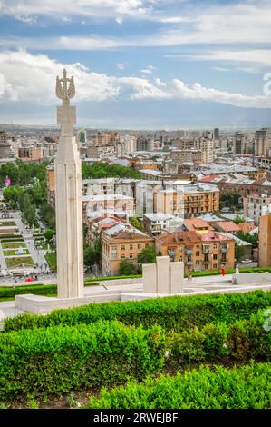 Foto di un grande monumento circondato dal verde e dagli edifici della capitale Erevan in Armenia Foto Stock