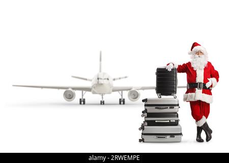 Babbo natale appoggiato su una pila di valigie di fronte a un aereo isolato su sfondo bianco Foto Stock