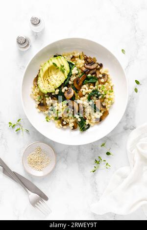 Couscous con avocado, spinaci e funghi champignon saltati con cipolla, vista dall'alto verso il basso Foto Stock