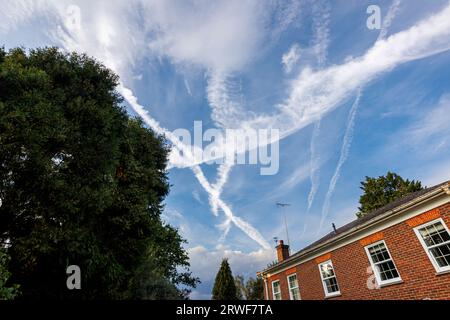 Tracce bianche di vapore incrociate da aerei diretti a Heathrow che formano schemi triangolari contro un cielo blu nel Surrey, nel sud-est dell'Inghilterra Foto Stock