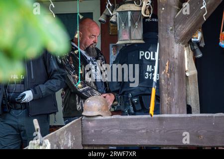 Jamel, Germania. 19 settembre 2023. Sven Krüger (M), un estremista di destra conosciuto in tutta la Germania, si trova tra gli agenti di polizia durante un'operazione di perquisizione sulla sua proprietà. Il ministro federale degli interni Faeser ha vietato l'associazione estremista di destra "Hammerskins Germany”, le sue propaggini regionali e la sottoorganizzazione "Crew 38”. Secondo il ministero, le forze di polizia hanno perquisito le case di 28 sospetti membri dell'associazione in dieci stati tedeschi la mattina presto. Credito: Jens Büttner/dpa/Alamy Live News Foto Stock