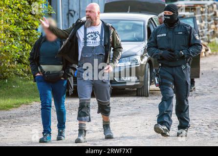 Jamel, Germania. 19 settembre 2023. Sven Krüger (M), un estremista di destra conosciuto in tutta la Germania, è accompagnato da agenti di polizia durante un'operazione di ricerca sulla sua proprietà. Il ministro federale degli interni Faeser ha vietato l'associazione estremista di destra "Hammerskins Germany”, le sue propaggini regionali e la sottoorganizzazione "Crew 38”. Secondo il ministero, le forze di polizia hanno perquisito le case di 28 sospetti membri dell'associazione in dieci stati tedeschi la mattina presto. Credito: Jens Büttner/dpa - ATTENZIONE: Le persone sono state pixelate per Legal/dpa/Alamy Live News Foto Stock