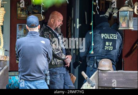 Jamel, Germania. 19 settembre 2023. Sven Krüger (M), un estremista di destra conosciuto in tutta la Germania, si trova tra gli agenti di polizia durante un'operazione di perquisizione sulla sua proprietà. Il ministro federale degli interni Faeser ha vietato l'associazione estremista di destra "Hammerskins Germany”, le sue propaggini regionali e la sottoorganizzazione "Crew 38”. Secondo il ministero, le forze di polizia hanno perquisito le case di 28 sospetti membri dell'associazione in dieci stati tedeschi la mattina presto. Credito: Jens Büttner/dpa/Alamy Live News Foto Stock