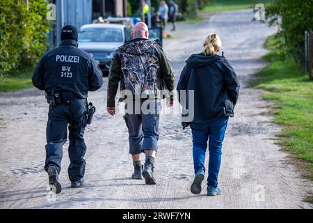 Jamel, Germania. 19 settembre 2023. Sven Krüger (M), un estremista di destra conosciuto in tutta la Germania, è accompagnato da agenti di polizia durante un'operazione di ricerca sulla sua proprietà. Il ministro federale degli interni Faeser ha vietato l'associazione estremista di destra "Hammerskins Germany”, le sue propaggini regionali e la sottoorganizzazione "Crew 38”. Secondo il ministero, le forze di polizia hanno perquisito le case di 28 sospetti membri dell'associazione in dieci stati tedeschi la mattina presto. Credito: Jens Büttner/dpa/Alamy Live News Foto Stock