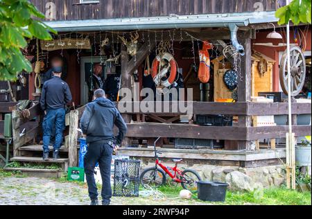 Jamel, Germania. 19 settembre 2023. Sven Krüger (Back M), un estremista di destra noto a livello nazionale, si trova tra gli agenti di polizia durante un'operazione di ricerca sulla sua proprietà. Il ministro federale degli interni Faeser ha vietato l'associazione estremista di destra "Hammerskins Germany”, le sue propaggini regionali e la sottoorganizzazione "Crew 38”. Secondo il ministero, le forze di polizia hanno perquisito le case di 28 sospetti membri dell'associazione in dieci stati tedeschi la mattina presto. Credito: Jens Büttner/dpa - ATTENZIONE: Le persone sono state pixelate per la ricerca legale/dpa/Alamy Live News Foto Stock