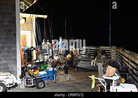 Le attrezzature da pesca sono sparse lungo la fine del molo di Jennette durante una gara di pesca notturna a Nags Head, North Carolina. Foto Stock