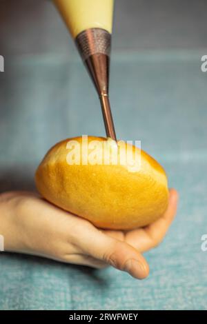 Krapfen ripieno a mano con crema di vaniglia. Dessert dalla Germania come impasto di ciambelle Foto Stock