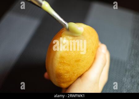 Krapfen ripieno a mano con crema di vaniglia. Dessert dalla Germania come impasto di ciambelle Foto Stock