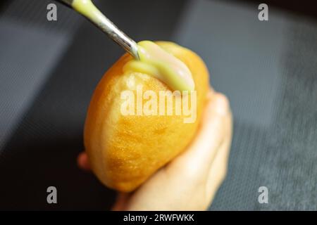 Krapfen ripieno a mano con crema di vaniglia. Dessert dalla Germania come impasto di ciambelle Foto Stock