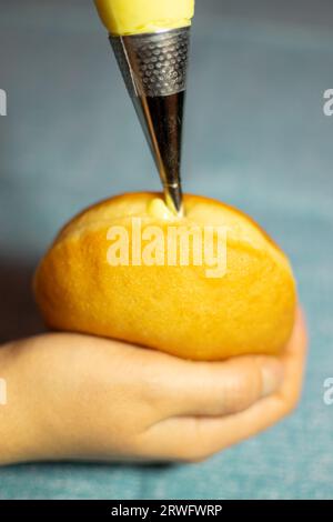 Krapfen ripieno a mano con crema di vaniglia. Dessert dalla Germania come impasto di ciambelle Foto Stock