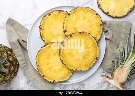 Fette di gustoso ananas maturo su un tavolo in marmo bianco, piatto Foto Stock