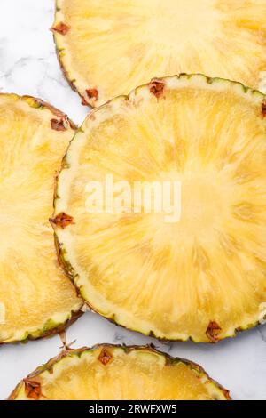 Fette di gustoso ananas maturo su un tavolo in marmo bianco, piatto Foto Stock