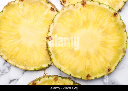 Fette di gustoso ananas maturo su un tavolo in marmo bianco, piatto Foto Stock