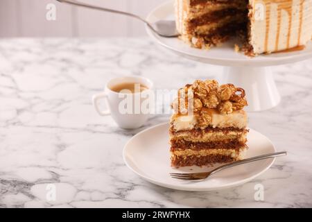 Gocciolatoio al caramello decorato con popcorn e pretzel su un tavolo in marmo bianco, spazio per il testo Foto Stock