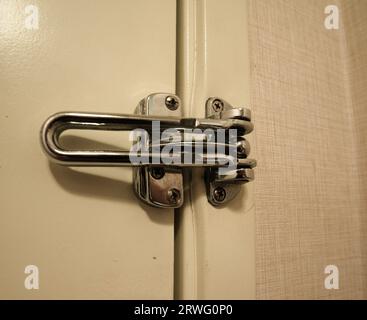 Chiusura classica in metallo, grande e robusta, che blocca la porta di un hotel o motel per evitare intrusi e ospiti indesiderati. Vista ravvicinata minacciosa di una porta e di una serratura molto usate. Foto di alta qualità Foto Stock