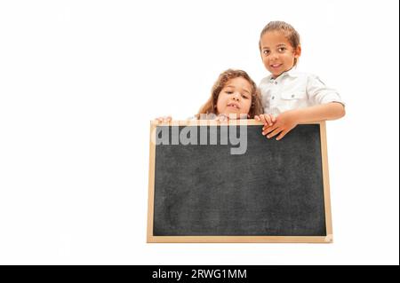 Inglese: Due bambini multietnici con i capelli lunghi tengono in mano una lavagna bianca su sfondo bianco Foto Stock