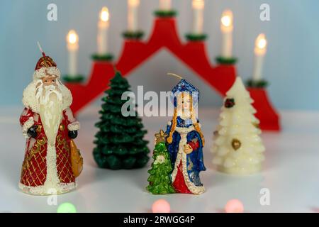 Babbo Natale, la fanciulla delle nevi e l'albero di Natale. Per festeggiare il nuovo anno, un candelabro natalizio con sette candele su sfondo blu invernale. Foto Stock