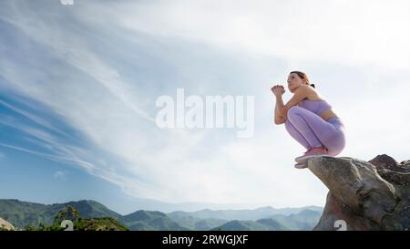 atleta sportiva seduta su rocce che guarda la vista delle montagne Foto Stock