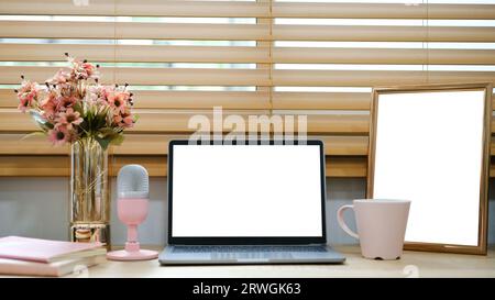 Notebook bianco con schermo vuoto posizionato sul tavolo vicino alla finestra. Foto Stock