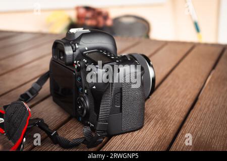 Camera Canon su un tavolo di legno. Hobby fotografico. Moderna tecnologia multimediale. Fotocamera ottica digitale. Body cam professionale. Concetto di intrattenimento. Foto Stock