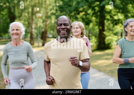 Anziano afroamericano che corre insieme ad altre persone anziane nel parco Foto Stock